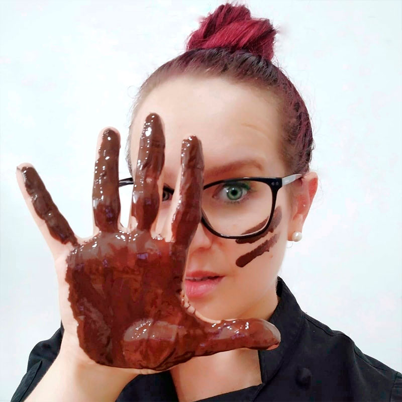 María, la repostera de Candy's, mostrando la palma de la mano cubierta de chocolate
