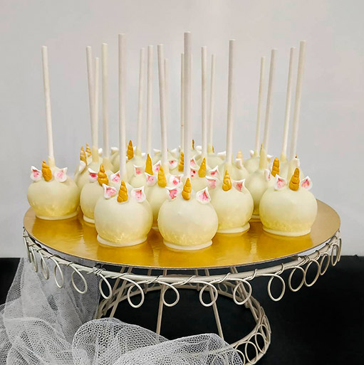 Cakepops con baño blanco colocados en una bandeja alta