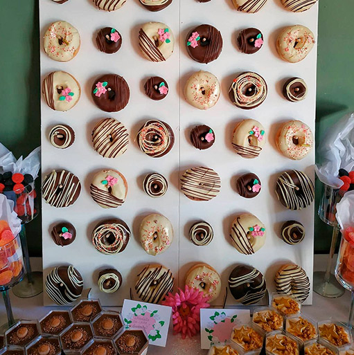Panel de donuts decorados y bandejas de dulces en una mesa de evento