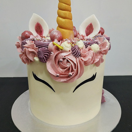 Tarta de unicornio con cuerno dorado, flores de crema y orejas de fondant