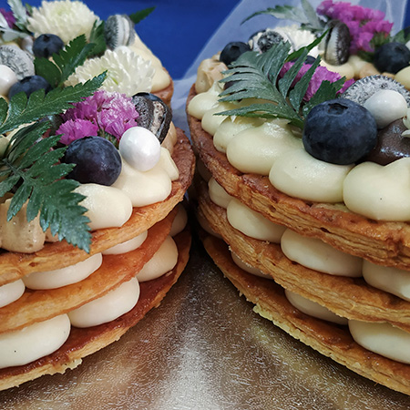Dos tartas de números de hojaldre decoradas con frutos rojos y flores