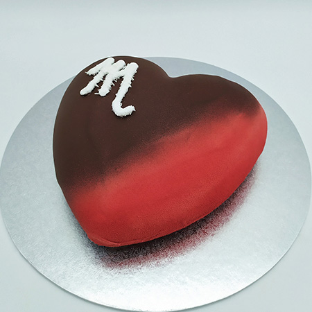 Tarta semifría en forma de corazón con glaseado rojo y una M dibujada