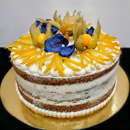 Tarta de zanahoria entera al descubierto, decorada con fruta y flores